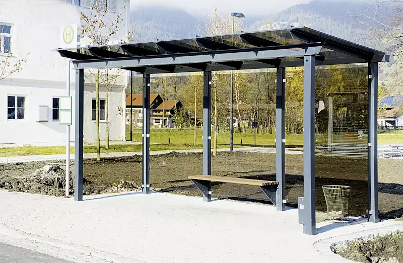 Wartehalle PEGASUS, Dachbreite x Dachtiefe 4800 mm x 2000 mm, auftragsbezogene Anpasssung Verglasung bronce, mit Sitzbank ARES und Abfallbehälter BRITS, Stahlkonstruktion in RAL 703 eisenglimmer