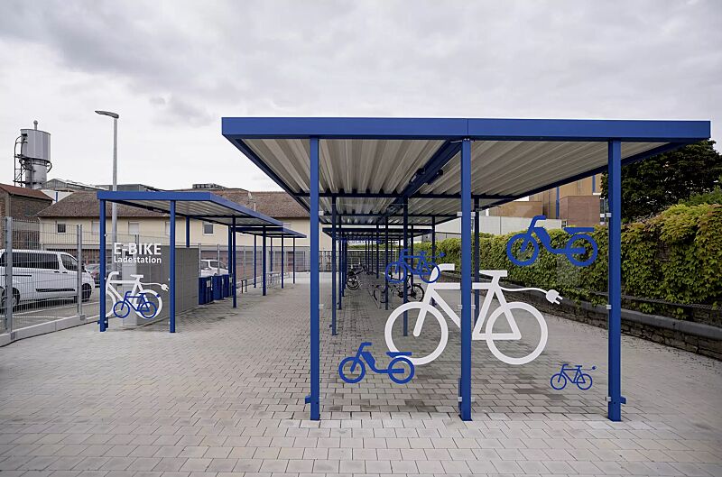 Fahrradüberdachung LUNA, Dachbreite x Dachtiefe 13660 mm x 4800 mm, Fahrradständer HEDLAND, Abstellanlage VELO-CONNECTOR, E-Bike-Ladestellenschrank AMARO, Scooter-Parker MANILA, Stahlkonstruktion in RAL 5010 enzianblau