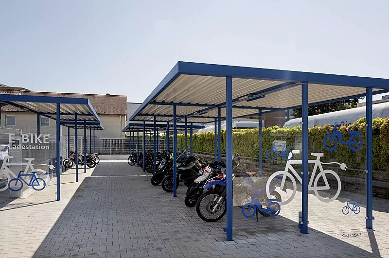 Fahrradüberdachung LUNA, Dachbreite x Dachtiefe 13660 mm x 4800 mm, Fahrradständer HEDLAND, Abstellanlage VELO-CONNECTOR, E-Bike-Ladestellenschrank AMARO, Scooter-Parker MANILA, Stahlkonstruktion in RAL 5010 enzianblau