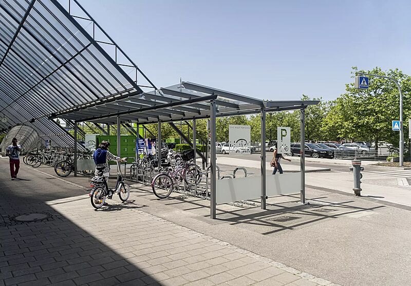 Fahrradüberdachung PEGASUS mit Trogdach, Dachbreite x Dachtiefe 9300 mm x 4500 mm, Seitenwände (Siebdruck nach Kundenvorgabe gegen Mehrpreis), Schließfachanlage SECURE, Fahrradparkern BERN, Stahlkonstruktion in RAL 9002 perldunkelgrau