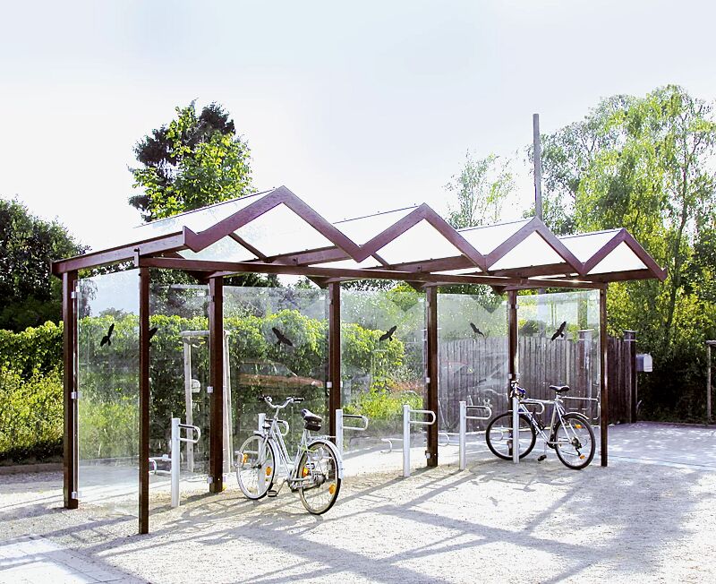 Fahrradüberdachung TANGENTA, einseitig, auftragsbezogene Anpassung mit Unterzug aufgrund erhöhter Schneelast, Dachbreite x Dachtiefe 6200 mm x 2250 mm, Rück- / Seitenwände ESG, Klarglas mit Raubvogelaufkleber, Stahlkonstruktion in RAL 4002 rotviolett