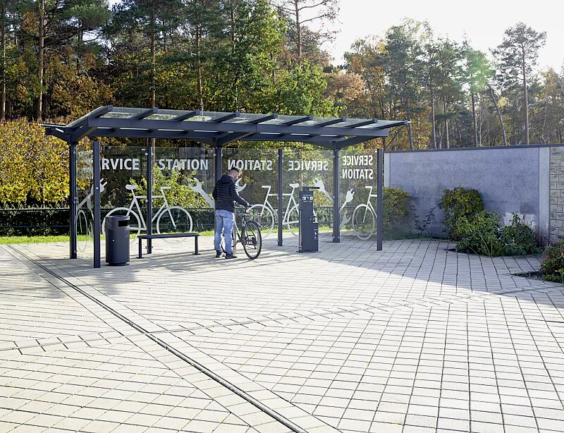 fahrradueberdachung-tucana__shoKAT0065901 Fahrradüberdachung TUCANA mit Trogdach, Dachbreite x Dachtiefe 6300 mm x 4600 mm, Rück- / Seitenwände ESG, Klarglas, Sitzbank RIMINI, Fahrradanlehnbügel FLINT, Servicestation ASSIST PREMIUM, Abfallbehälter CIMA, Stahlkonstruktion in RAL 7016 anthrazitg...