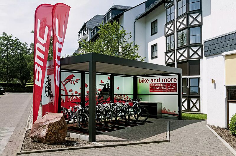 multiport-rad__shoKAT0033453 MULTIPORT® Rad als Mountain-Bike-Station mit auftragsbezogener Anpassung, Dachbreite x Dachtiefe 5970 mm x 3060 mm, Rück- und Seitenwände ESG satiniert, vorgehangen (Werbeaufdruck kundenseits), mit Fahrradständer MISSOURI, Stahlkonstruktion in RAL 7021...