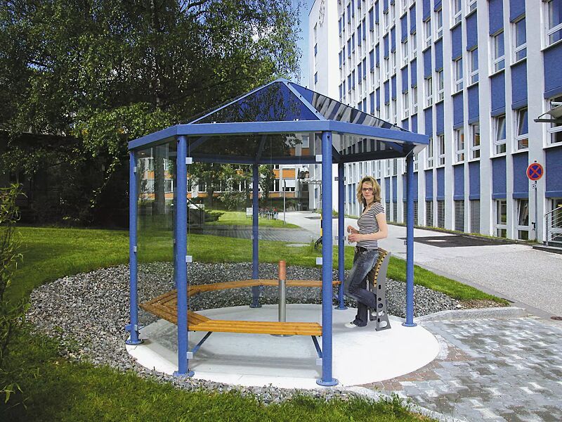 Einzel-Pavillon AQUA, mit 5 Holzsitzbänken, Anlehnstütze RELIEF und Ascher CYCAS, Dacheindeckung VSG bronce getönt (auftragsbezogene Anpassung), 6 Seitenwandscheiben ESG Klarglas, Stahlkonstruktion in RAL 5015 himmelblau