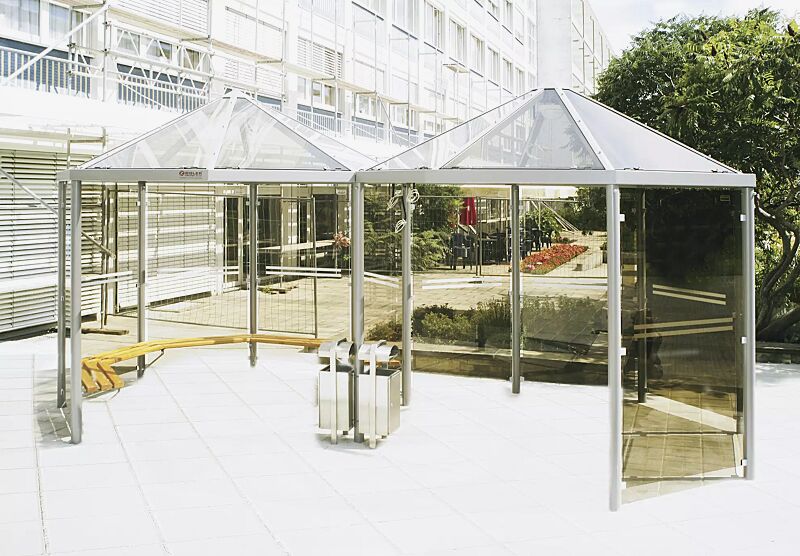 Zweier-Pavillon AQUA mit umlaufenden Holzsitzbänken, 10 Seitenwandscheiben ESG bronce getönt (auftragsbezogene Anpassung), mit Siebdruckstreifen, Dacheindeckung VSG Klarglas, Stahlkonstruktion in DB 703 eisenglimmer