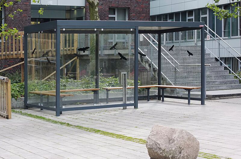 raucherunterstand-tobacco__shoKAT0020627 Raucherunterstand TOBACCO, Dachbreite x Dachtiefe 4700 mm x 2400 mm, 2 zweiseitige Sitzbänke, 1 Windschutzwand 2300 mm mit vorderer Stütze, Seiten- / Rück- / Windschutzwand mit Raubvogelaufklebern, Stahlkonstruktion in RAL 7016 anthrazitgrau