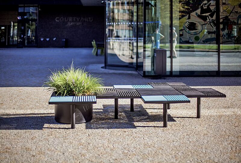 Sitz PIXEL CITÉ, bestehend aus verschiedenen Segmenten, mit Robinienholzbelattung in RAL 5024 pastellblau bzw. RAL 9011 graphitschwarz, Stahlteile in RAL 9011 graphitschwarz