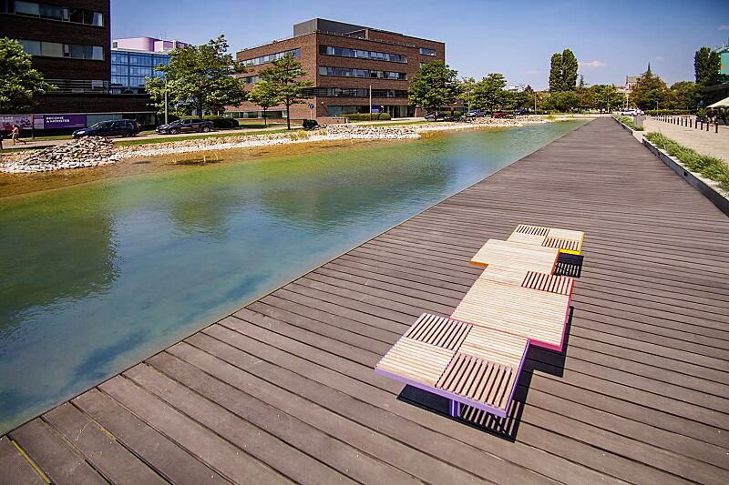 sitz-pixel-cit%C3%A9__shoKAT0059482 Sitz PIXEL CITÉ, bestehend aus verschiedenen Segmenten, mit Robinienholzbelattung, Stahlteile in RAL 2004 reinorange, RAL 3020 verkehrsrot, RAL 4010 telemagenta, RAL 4005 blaulila und RAL 1021 rapsgelb