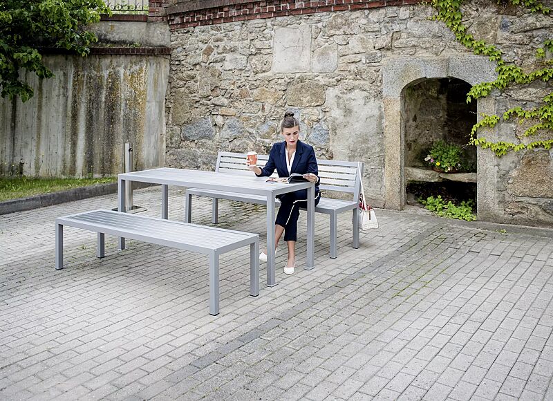 Sitzbank LIGURIA mit und ohne Rückenlehne, zum freien Aufstellen, mit Edelstahlauflage, Stahlgestell in RAL 9007 graualuminium sowie Tisch LIGURIA und Ascher FINTWIN