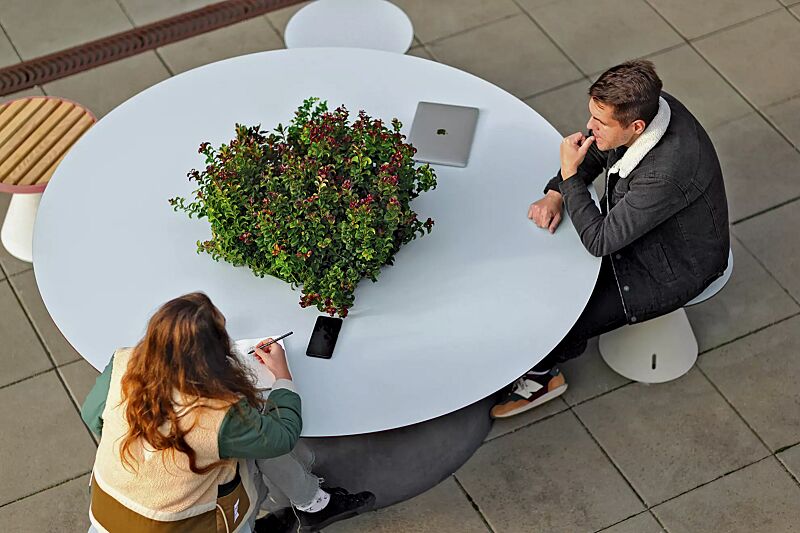 Tisch CONICS mit HPL-Auflage in Glacier blue 0706, inkl. Pflanzeinfassung, HPC-Beton in dunkelgrau und Sitze CONICS mit HPL-Auflage in Glacier blue 0706 sowie Jatobaholzbelattung, HPC-Beton in hellgrau, Stahlteile in RAL 4010 telemagenta