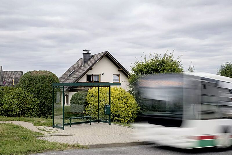 Wartehalle AQUILA, Dachbreite x Dachtiefe 3180 mm x 2165 mm, zum Aufdübeln bei -200 mm, Rück- / Seitenwände ESG, Klarglas, Abfallsammler DERBY, Drahtgittersitz TARVIS, Stahlkonstruktion in RAL 6005 moosgrün